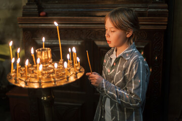 Young boy praying and lighting candles in an Orthodox church in Georgia. Moments of reverence, faith, and spiritual reflection