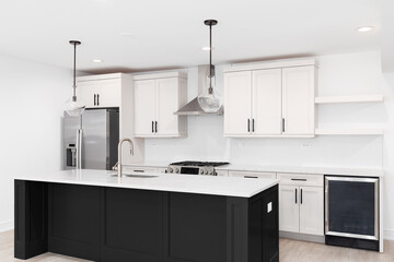 A modern kitchen with off white cabinets, black island with a white marble countertop, stainless steel appliances, and white herringbone tile backsplash. No brands or labels.