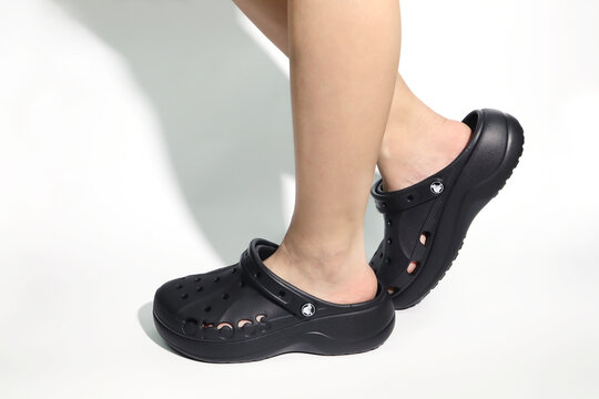 nice rubber black Crocs shoes are worn by young girls on white floor white background display wearing crocs lifestyle sandals at shoes store during opening new model crocs footwear diy design contest
