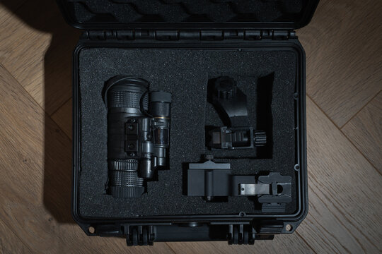 Professional night vision monocular with mounts, neatly packed in a protective shockproof case with a foam insert on a wooden background.