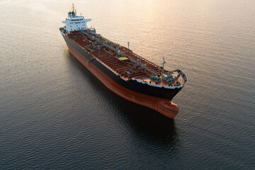A huge oil tanker transports crude oil through the calm waters of the Baltic Sea at sunset, aerial...