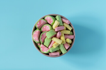 Colored marshmallow with watermelon flavor in a porcelain bowl on a blue background, top view, copy...