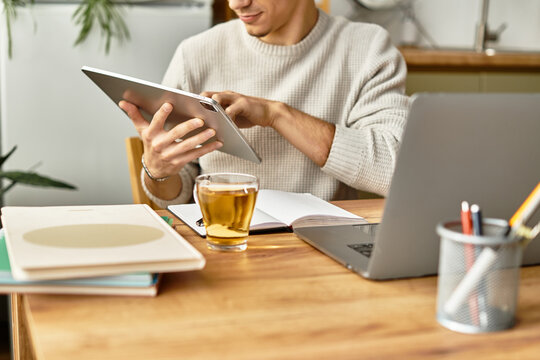 Focused young man engaged in work while enjoying tea at a stylish home workspace