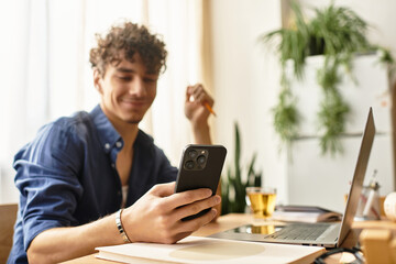 Stylish young man engaging with smartphone while working in a bright office setting