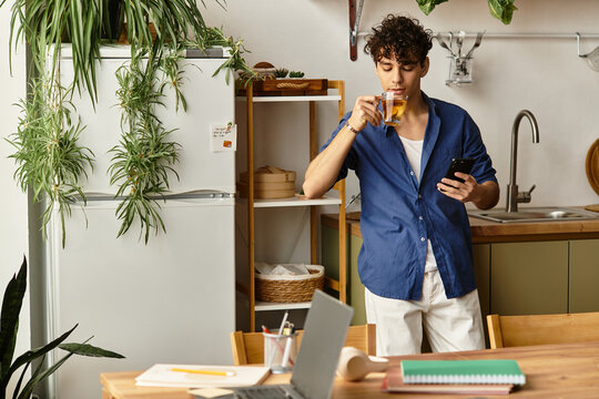 Handsome young man enjoying tea while checking his phone in a stylish kitchen