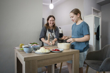 Happy family indoor. Mother And Daughter Baking Pizza In Kitchen Together
