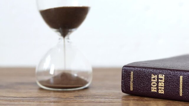 Hourglass with sand and holy bible book. Christian biblical concept of time and patience.