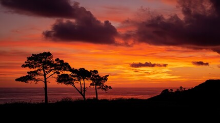 At sunset, the silhouettes of trees reflect the orange and red sky above the lake, with clouds overhead and mountains in the distance.