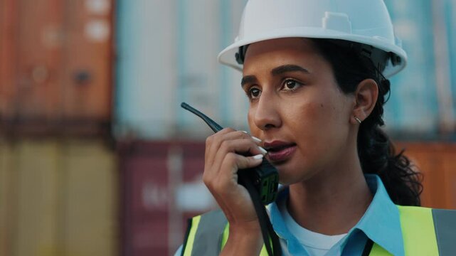Woman, Giving Commands by Radio for Communication, Latino Supervisor Wearing Hard Hat. Female Worker Standing at Building Site Using Walkie Talkie For Communicating with Team. Engineer Concept