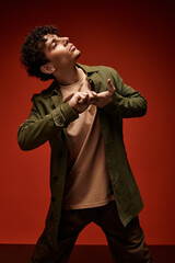 Stylish young man posing confidently against a vibrant red backdrop in a creative setting