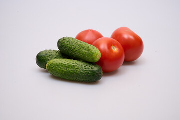 green cucumbers and red tomatoes on a white background