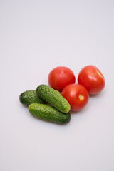 green cucumbers and red tomatoes on a white background