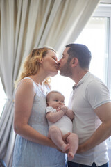 Mom and dad holding baby in their arms. family photo