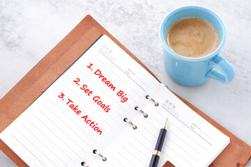 Dream Big, Set Goals, Take Action - words in notebook with cup of coffee, life and business motivational inspirational concept
