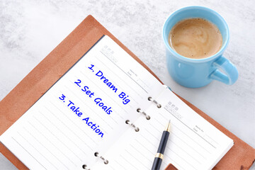 Dream Big, Set Goals, Take Action - words in notebook with cup of coffee, life and business motivational inspirational concept
