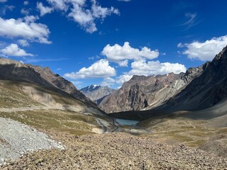 Beautiful landscape of turquoise Ala-Kul Lake in the Tien Shan mountains with white foggy clouds in...