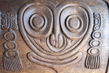 Intricate Wooden Carving with Stylized Face and Symmetrical Tribal Patterns