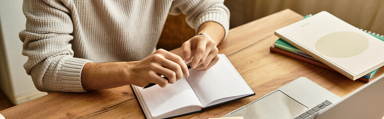 Stylish young man writing notes on a wooden desk in a cozy indoor setting