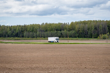 Logistics Truck Driving Through Countryside with Farmland and Forest – Freight Transport in Rural...