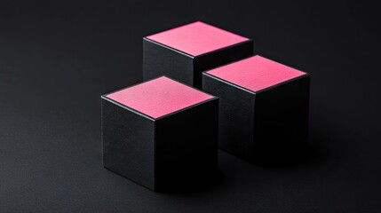 Three small black boxes with pink tops on a dark surface.
