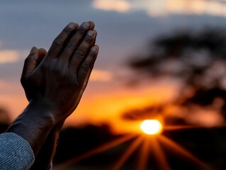 Hands clasped in prayer at sunset (3)