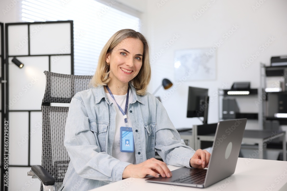 Poster smiling engineer working with laptop at table in office