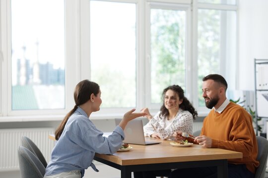 Colleagues eating and chatting during lunch break in office
