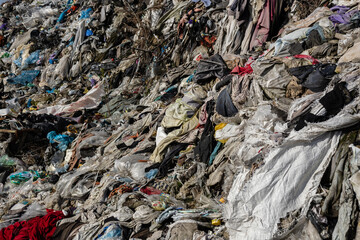 Textiles and clothing are strewn across a landfill, highlighting the issues of waste management and...
