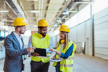 Engineers and Technicians Collaborating in a Factory Setting Wearing Safety Gear