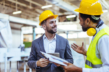 Fototapeta na wymiar Engineers Discussing Industrial Projects in Modern Factory Setting