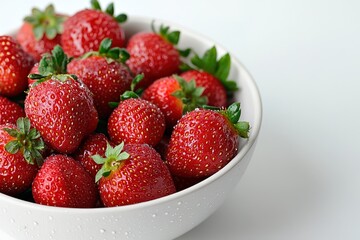A bowl of bright red strawberries with water droplets on their surface, placed on a smooth white backdrop