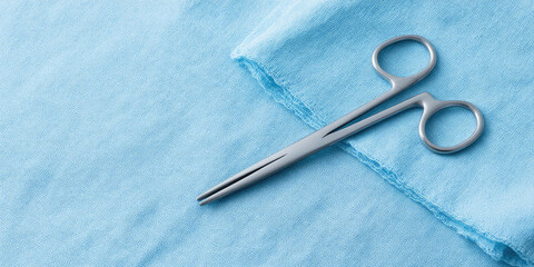 Fototapeta premium Surgical scissors resting on a blue fabric surface. Medical tool and sterile equipment