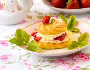 Cream puffs cakes or profiterole filled with whipped cream and strawberries
