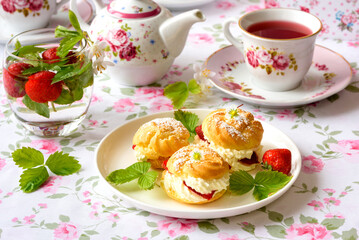 Cream puffs cakes or profiterole filled with whipped cream and strawberries
