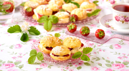 Cream puffs cakes or profiterole filled with whipped cream and strawberries