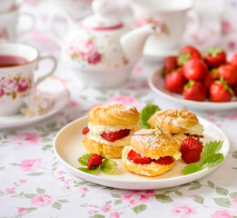 Cream puffs cakes or profiterole filled with whipped cream and strawberries