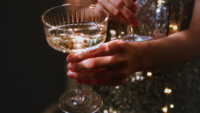 A beautiful girl holds glasses of champagne in her hands. Le coup cocktail glasses. Celebrates the New Year or a corporate holiday. Disco or retro style.