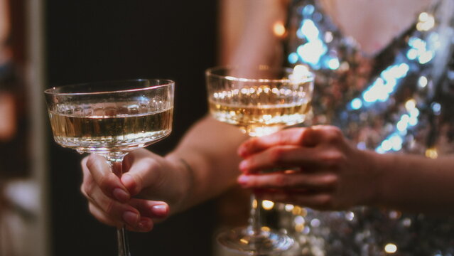 A beautiful girl holds glasses of champagne in her hands. Le coup cocktail glasses. Celebrates the New Year or a corporate holiday. Disco or retro style.