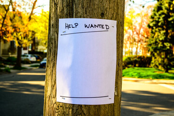Blank help wanted  handbill stapled to a wooden utility pole out of focus street scene in background room for text white paper 8.5 by 11 blank