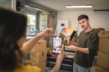 woman record video of man choose color for wall from color palette