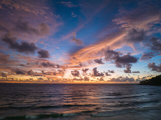 A stunning scene of a vivid sunset with pink and orange hues illuminating the sky over Karon beach...