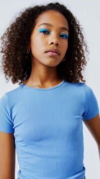Portrait of a Young Girl: Curly Hair, Blue Eyeshadow, and a Serious Facial Expression in a Vertical Video