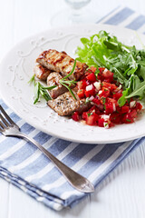 Fried pork tenderloin with tomato salsa. Bright background. Close up.	