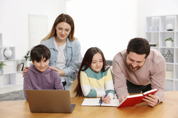 Fototapeta premium Parents helping their kids with homework at wooden table indoors