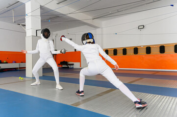 Female fencer lunging forward to strike opponent indoors.