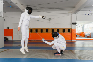Female fencers making simultaneous epee hit in indoor duel.