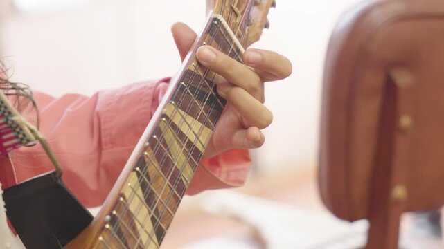 Close-up of a person playing a charango, a small Andean stringed instrument. The focus is on the musician's hands and the instrument, highlighting the intricate fingerwork and the unique sound