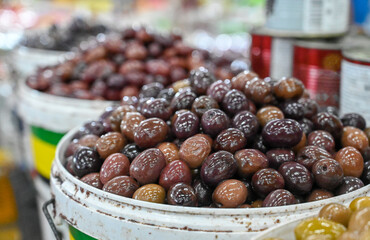 Olives for sale at the market. Fresh olives in a bowl. Black olives, close up. 