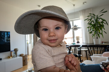 Stockholm, Sweden A six-month-old baby girl wears a large baseball hat.