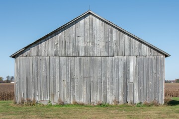 Weathered wooden barn against a clear blue sky.